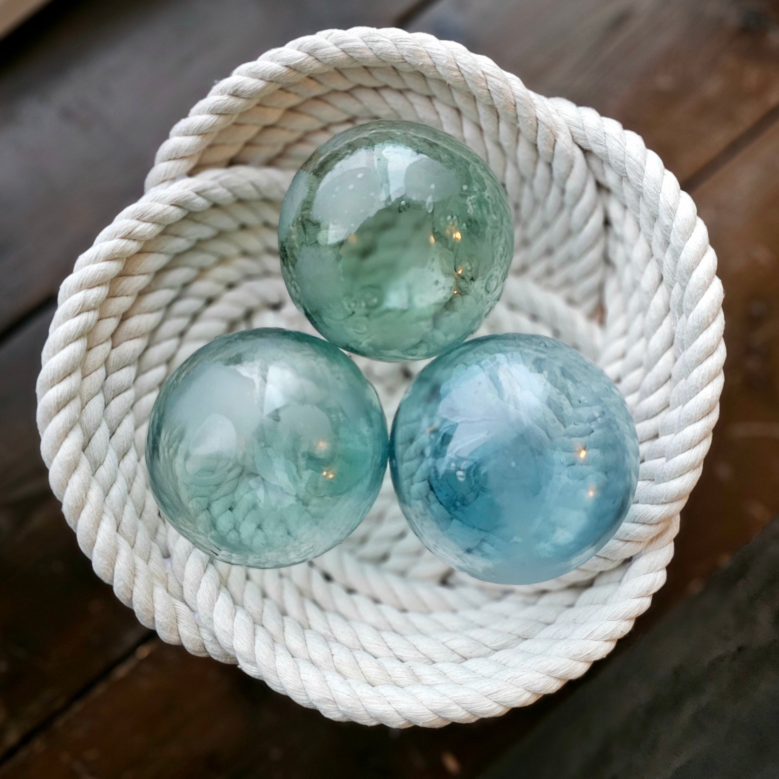 Three glass spheres on a woven white basket on a wooden surface